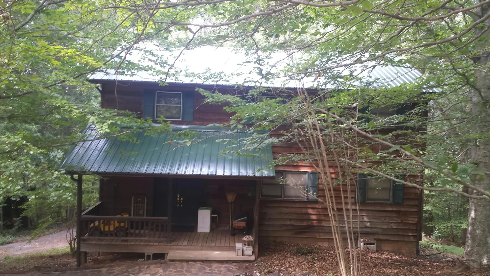 Green metal roof and covered porch on a log cabin in Allen