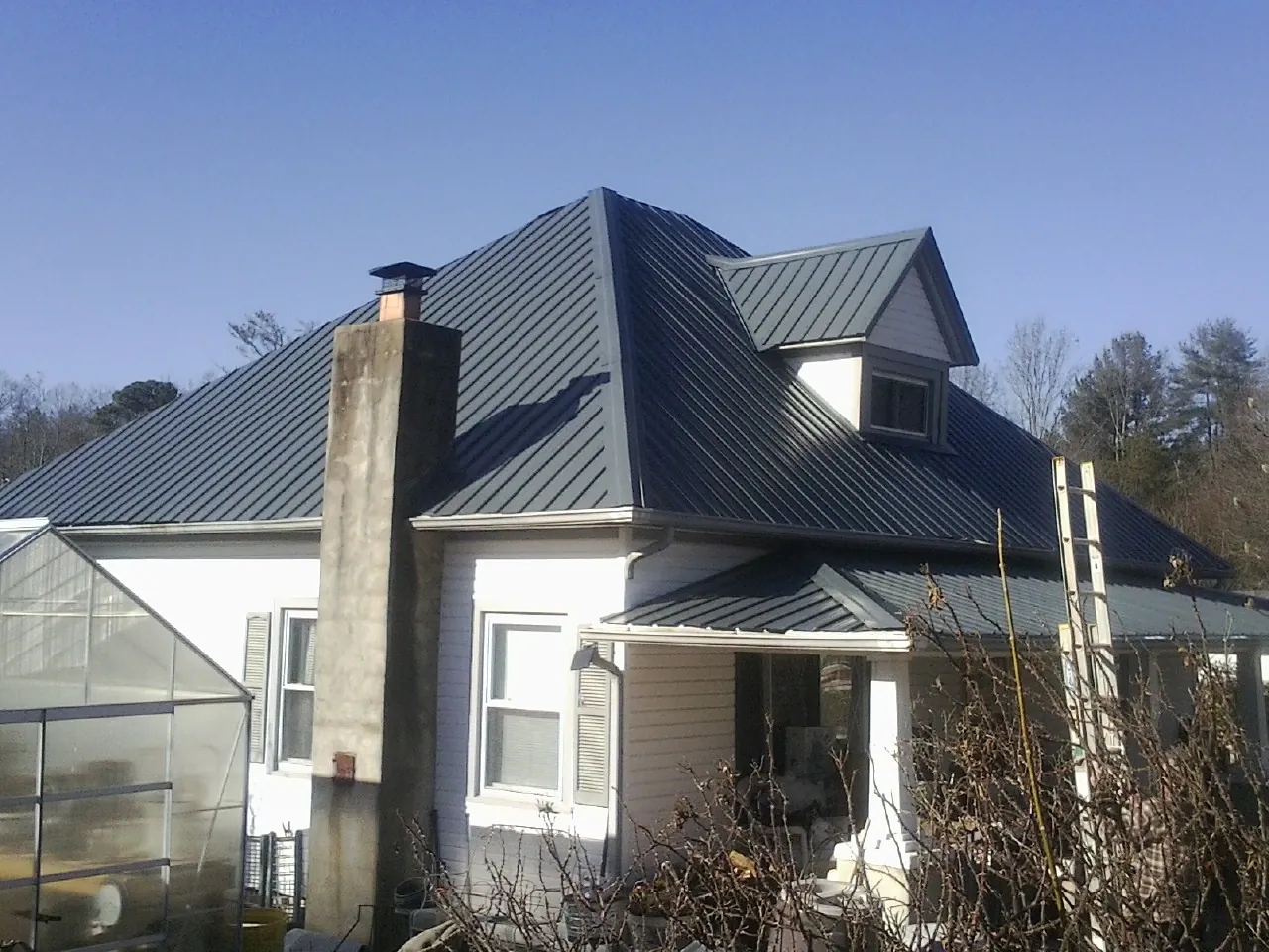Dark blue standing seam metal roof on a white farmhouse with dormer — Slate & Tile Roof Repair by Roofing Brothers in Allen