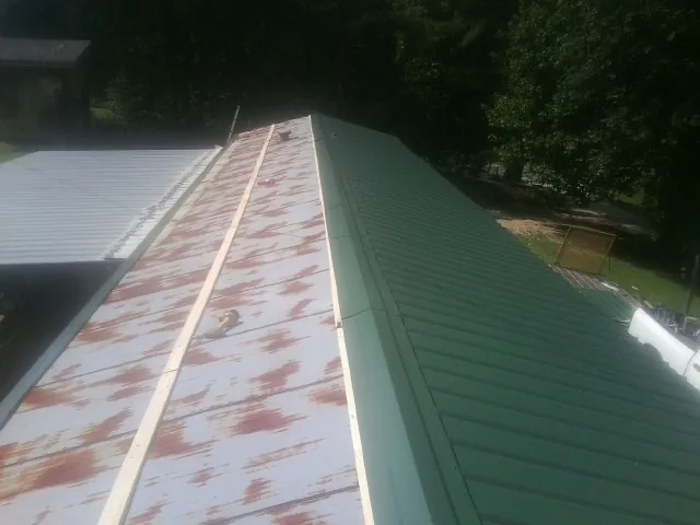 Old rusted panels beside newly installed green metal roofing — Wind Damage Roof Repair by Roofing Brothers in Allen
