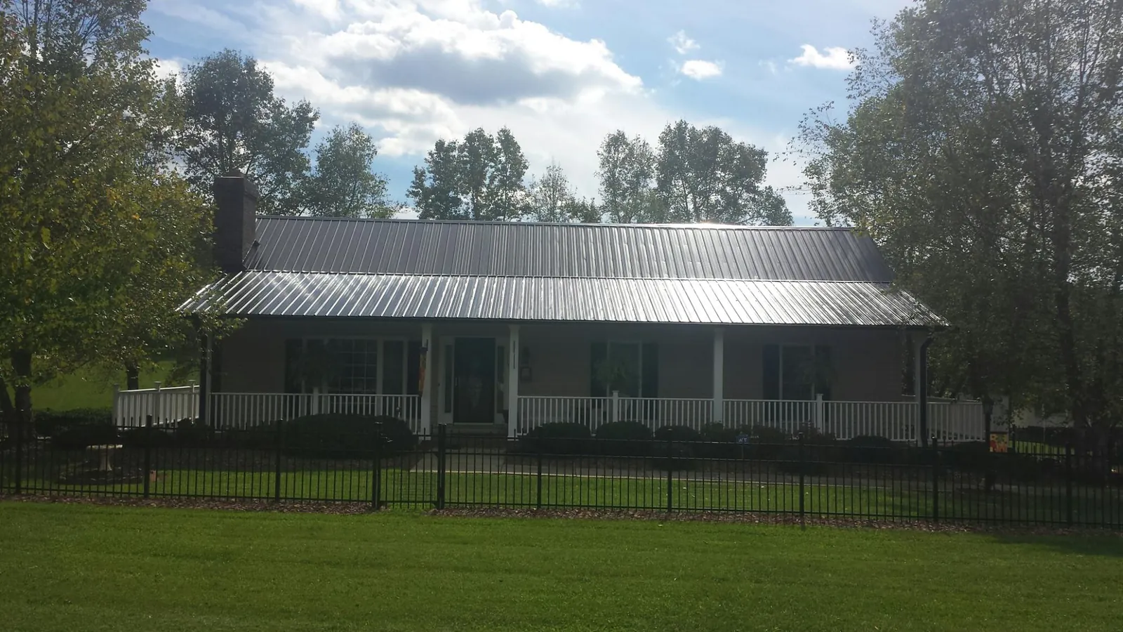 Gray metal roof on a brick ranch with a full width front porch — Gutter Guard Installation work by our crew in Allen